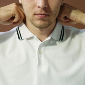 Close-up portrait of a man adjusting his polo shirt collar, artistic lighting.